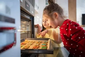 deux petites filles regardent les sablés de Noël à leur sortie du four