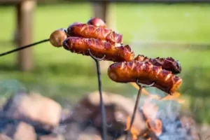 des saucisses grillées sur un feu de camp pendant un WE original avec les enfants autour de Paris