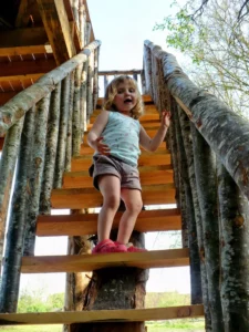 une enfant monte en toute sécurité dans la cabane perchée dans les arbres de Family Ecolodge Puisaye, une cabane pour les familles dans le Loiret, Centre Val de Loire, France
