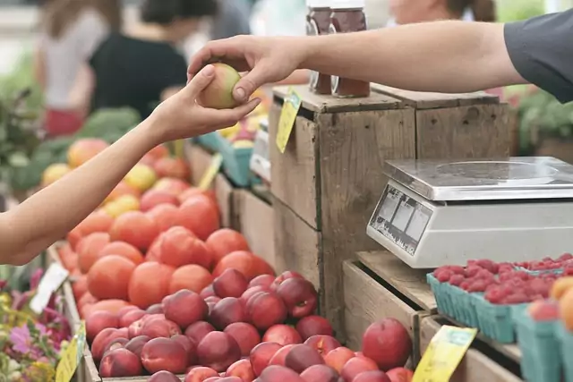 un vendeur donnant une pomme à un client un jour de marché
