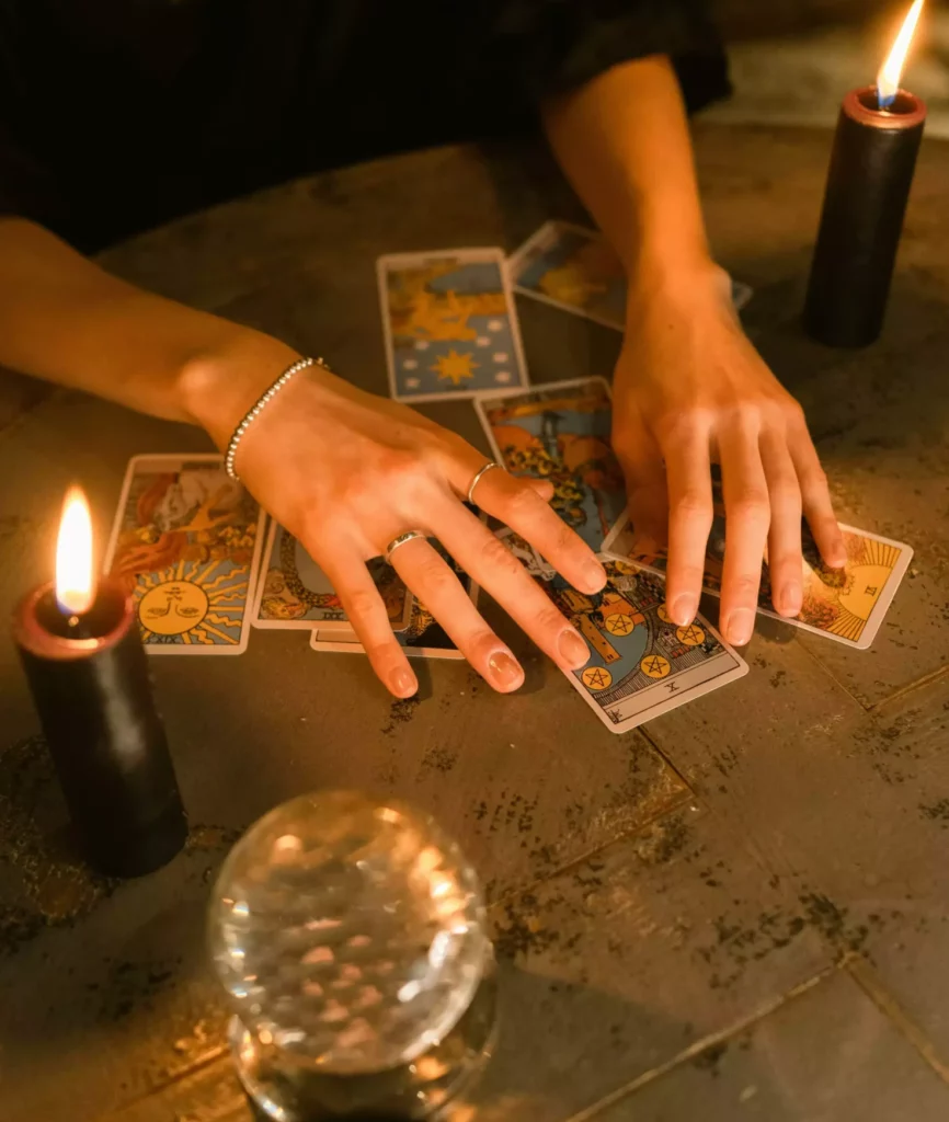 mains d'une voyante avec un jeu de cartes, une boule de cristal et des bougies