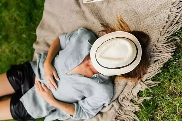 une femme fait la sieste, allongée dans l'herbe, c'est la Slow life : apprendre à prendre le temps pendant ses vacances