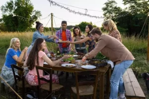des amis mangent autour d'une grande table, en plein air, au cours d'un week-end entre amis pas cher à Family Ecolodge Puisaye