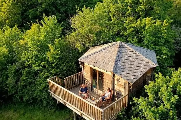 Un couple prend l'apéritif sur la terrasse d'une cabane perchée pour dormir dans les arbres à Family Ecolodge.