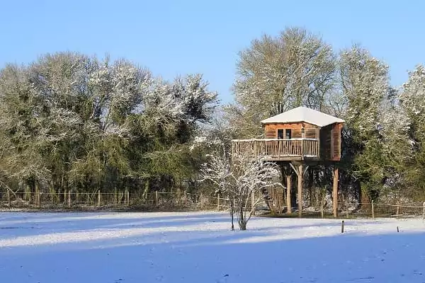 Une cabane perchée pour dormir dans les arbres sous la neige.