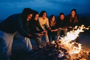 Des amis sont réunis autour d'un feu de camp dans une ambiance chaleureuse lors d'un EVJF ecolo à Family Ecolodge.