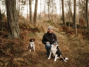 un homme en promenade avec ses 2 chiens dans la forêt en automne, pendant des vacances pet friendly en France
