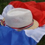 Un chapeau de paille posé sur une pelouse verte à côté d'un petit drapeau français évoquant une ambiance estivale de match de football de la coupe du monde.