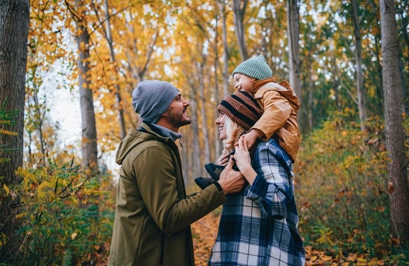 une famille, papa, maman ,enfant, se promènent en forêt en automne