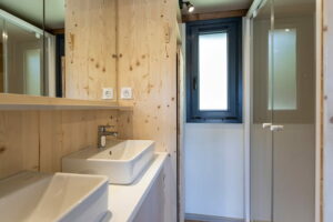 Salle de bain privative pour des vacances d'automne en lodge en bois entouré d'arbres roux.